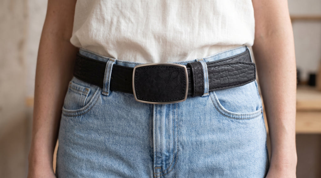 Woman wearing light-wash jeans and a black bull neck texture western belt with a silver-tone buckle