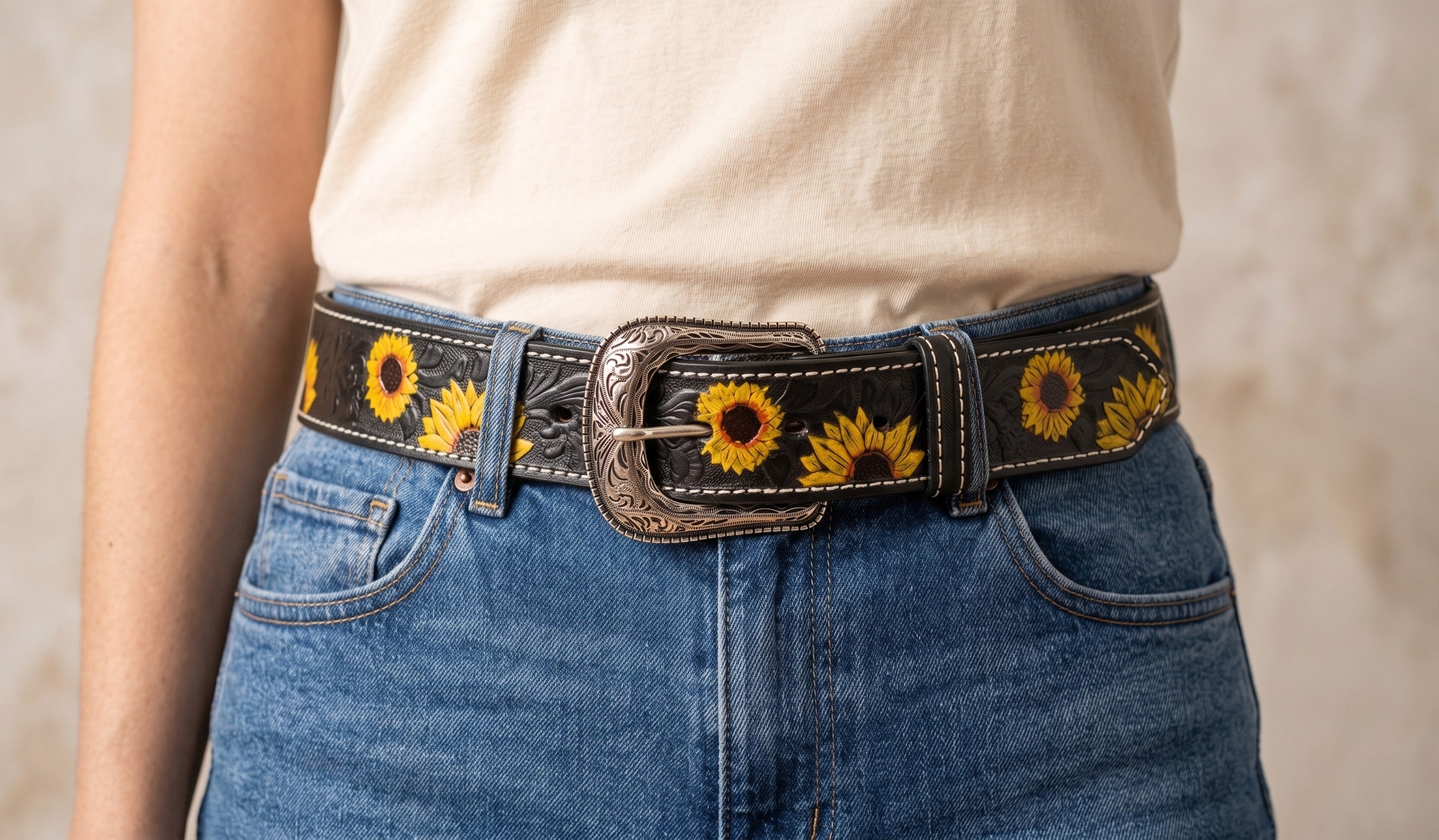 Mujer con cinturón negro de girasoles puesto sobre mezclilla