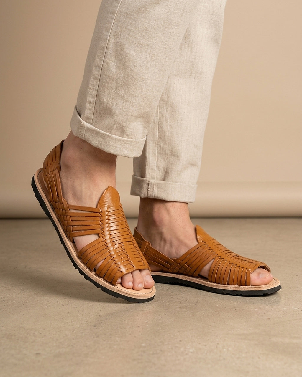 Man in beige linen trousers wearing men's honey brown open-toe leather huarache sandals