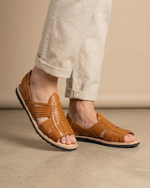 Hombre con pantalón de lino beige calzando huaraches de piel para hombre color miel, de punta abierta