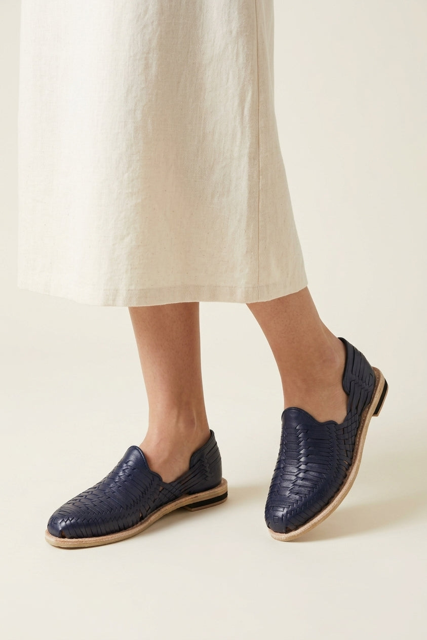 Women's navy blue huaraches paired with light linen; AI-generated styling image