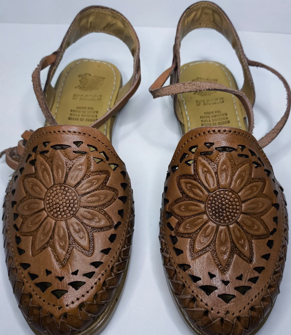 Top view of brown closed toe leather huaraches for women: sunflower in relief, triangular cutouts and long ankle ties