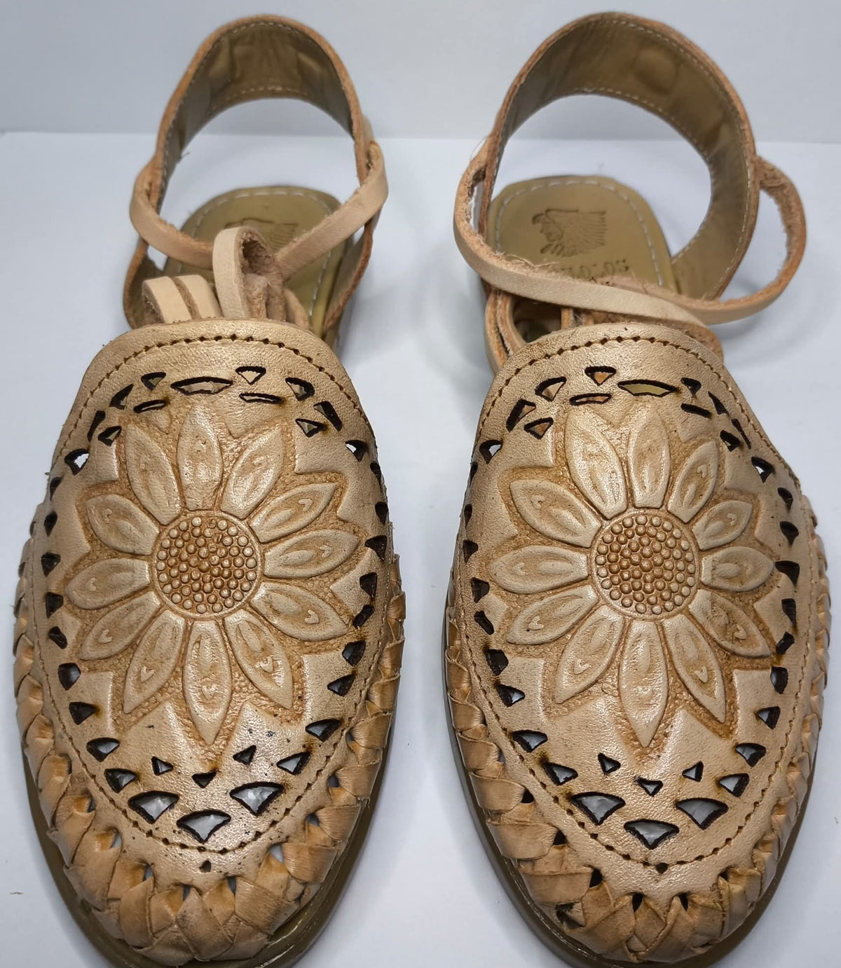 Top view of honey closed toe leather huaraches for women: sunflower in relief and a border of triangular cutouts