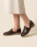 Women's dark brown leather huaraches worn with a natural linen skirt; AI-generated lifestyle image