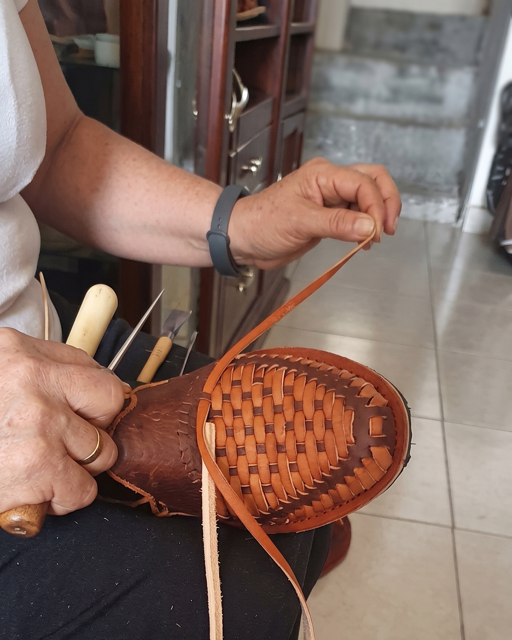 Artisan hand-weaving the leather strips of a huarache