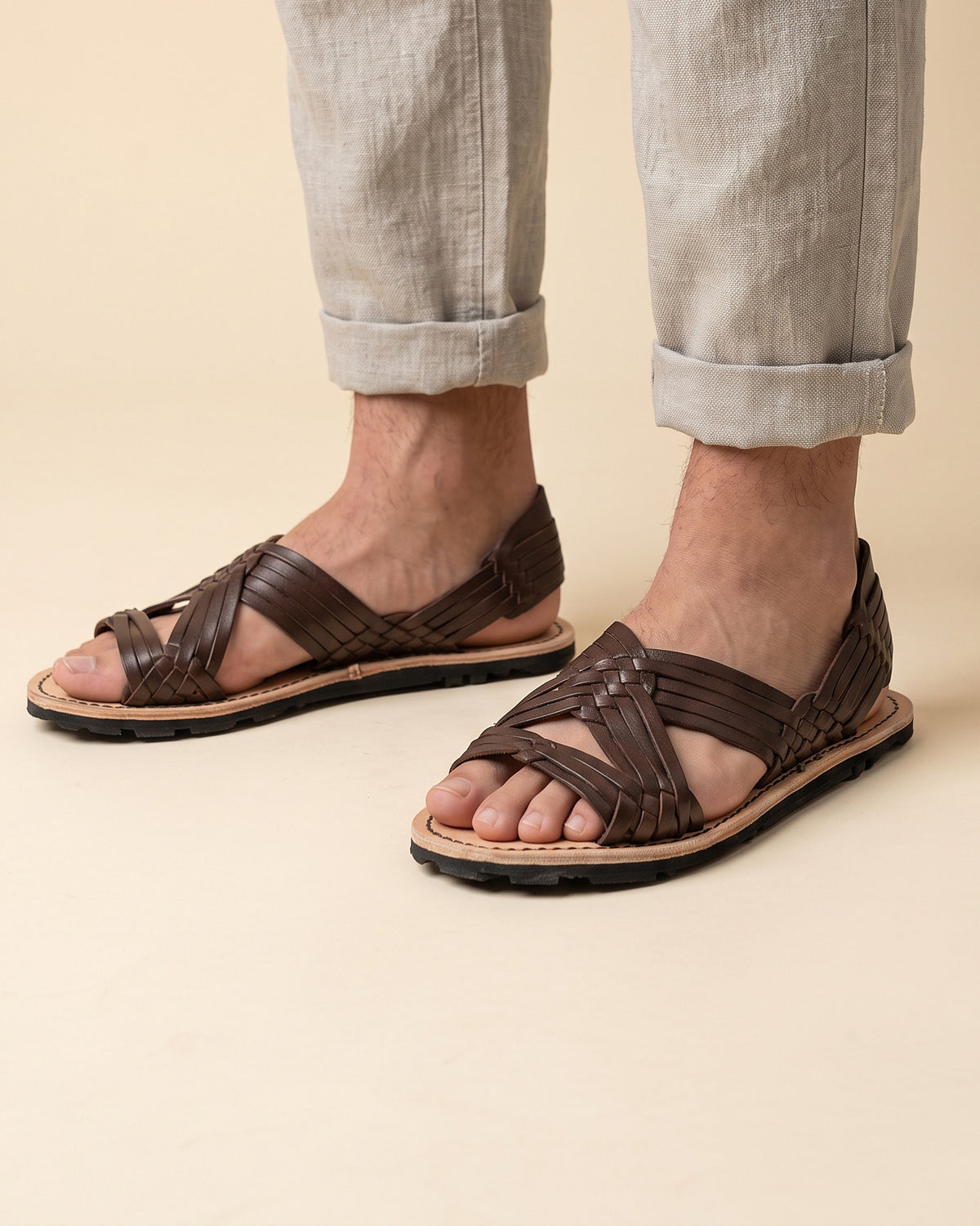 Huaraches de araña cafés para hombre, de vaqueta con suela de hule, puestos con pantalón de lino remangado (imagen generada con IA)