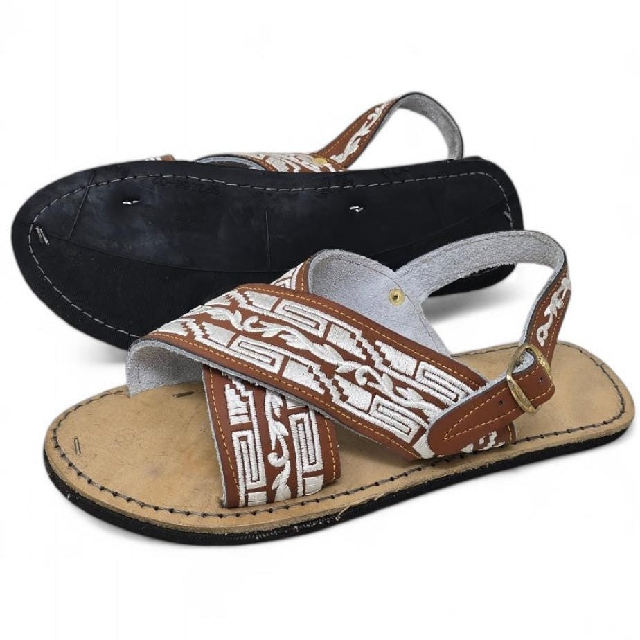 Brown and white cross strap huarache sandals for men, one turned over to show the tire sole