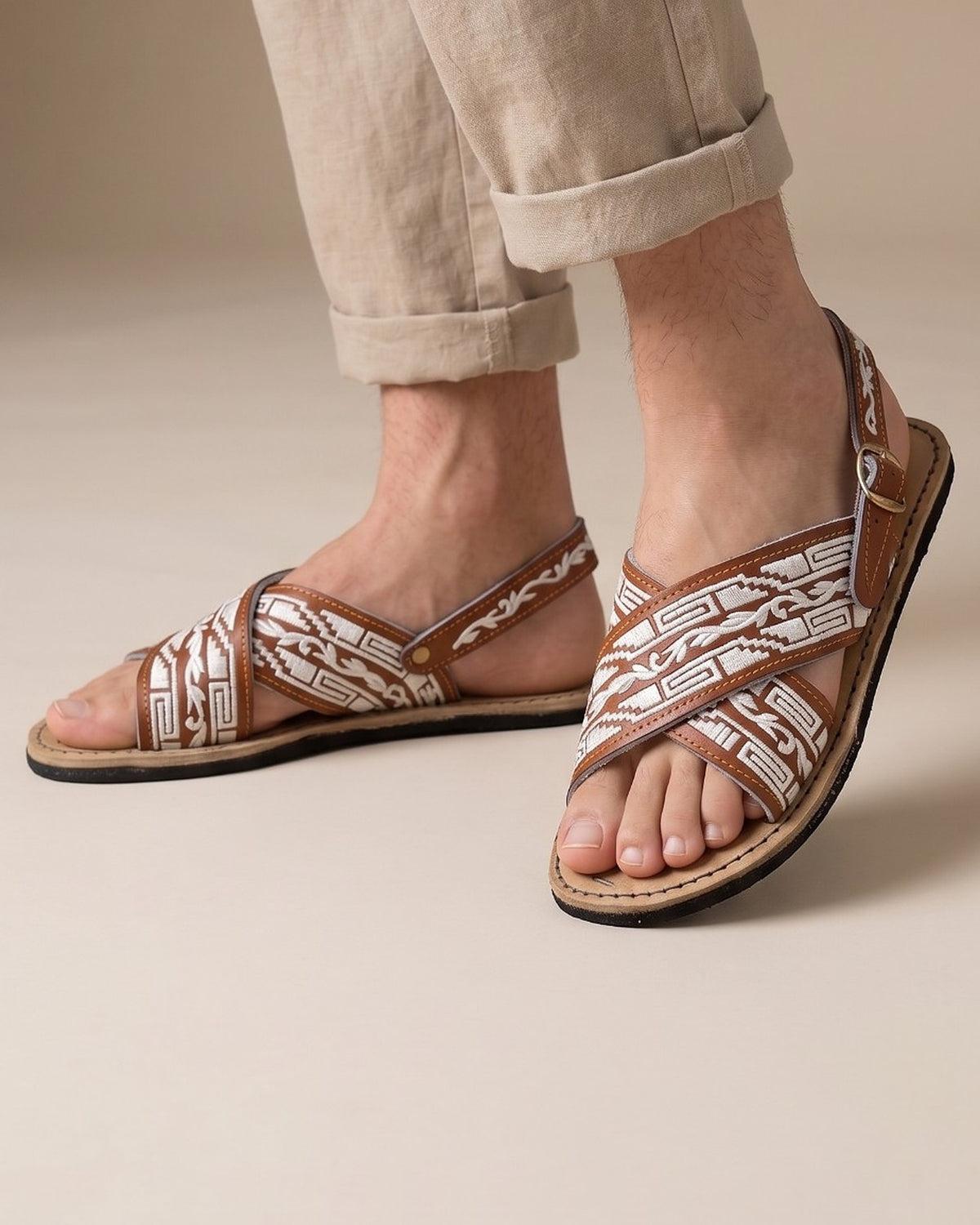 Man in rolled-up linen pants walking in brown and white embroidered Mexican huarache sandals