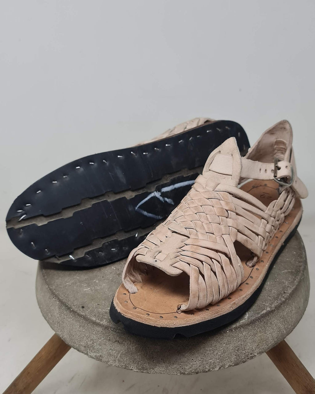 Huarache sandals with tire tread soles: one flipped to show the recycled tire tread and the nail tips through the rubber