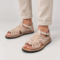 Man in beige linen pants wearing men's pachuco huarache sandals in natural leather with ankle strap and tire soles