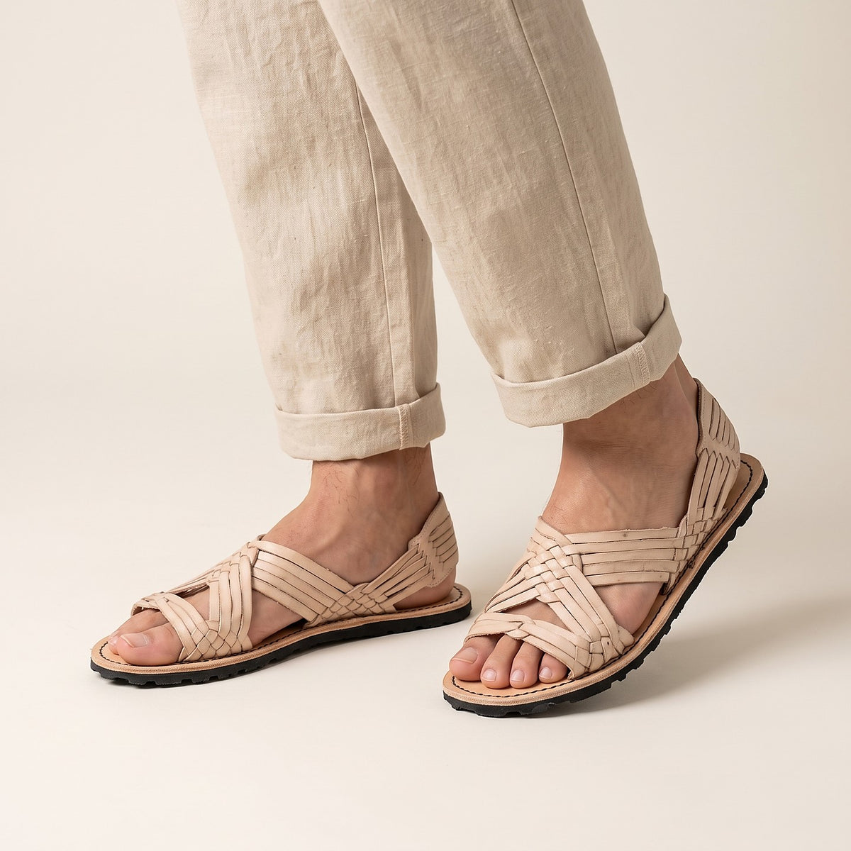 Men's open toe woven leather huarache sandals, natural leather, rubber sole, worn standing, linen pants with rolled cuffs