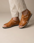 Man in beige linen pants wearing tan leather pachuco huarache sandals for men with open toe and tire sole